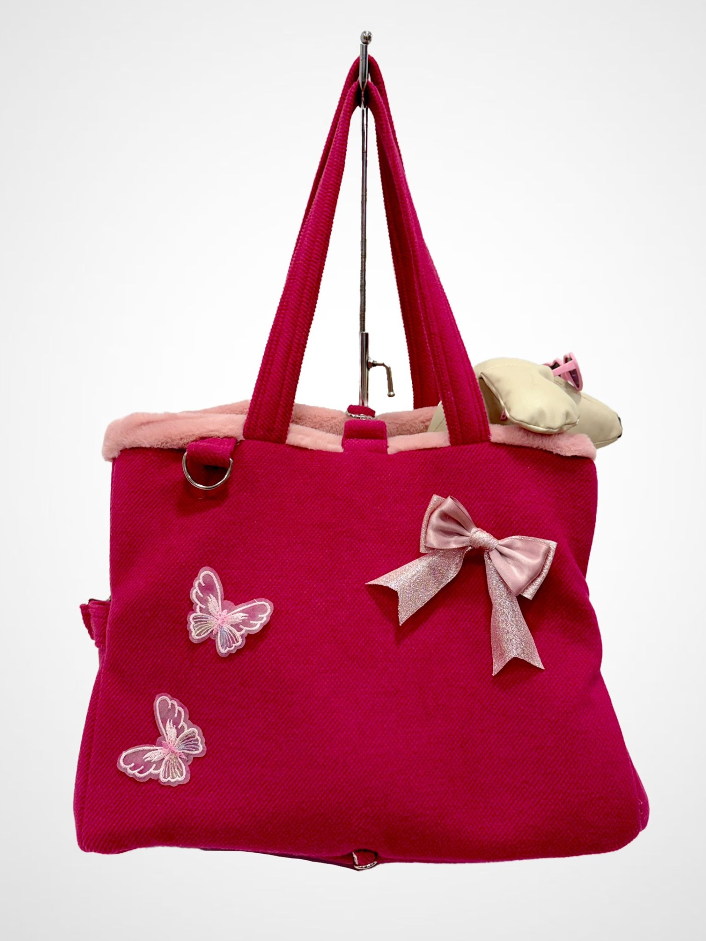 Mala cor-de-rosa com laço, borboletas bordadas e interior em pêlo rosa, pendurada em gancho