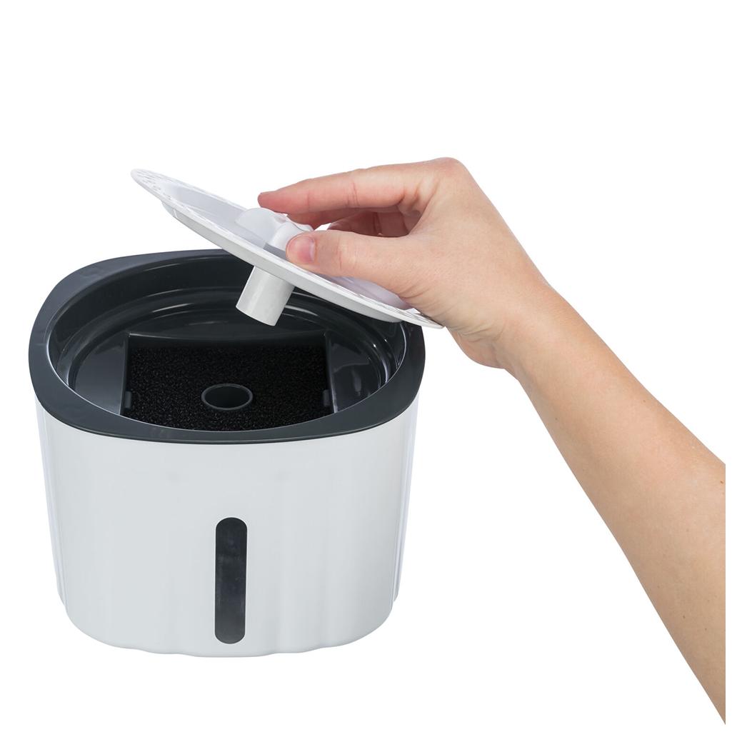 Recipiente branco com tampa preta e filtro preto, mão segurando tampa.