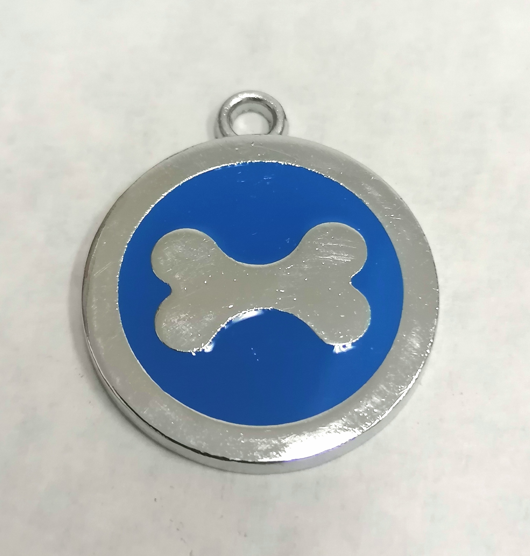 Medalha metálica redonda com osso branco sobre fundo azul