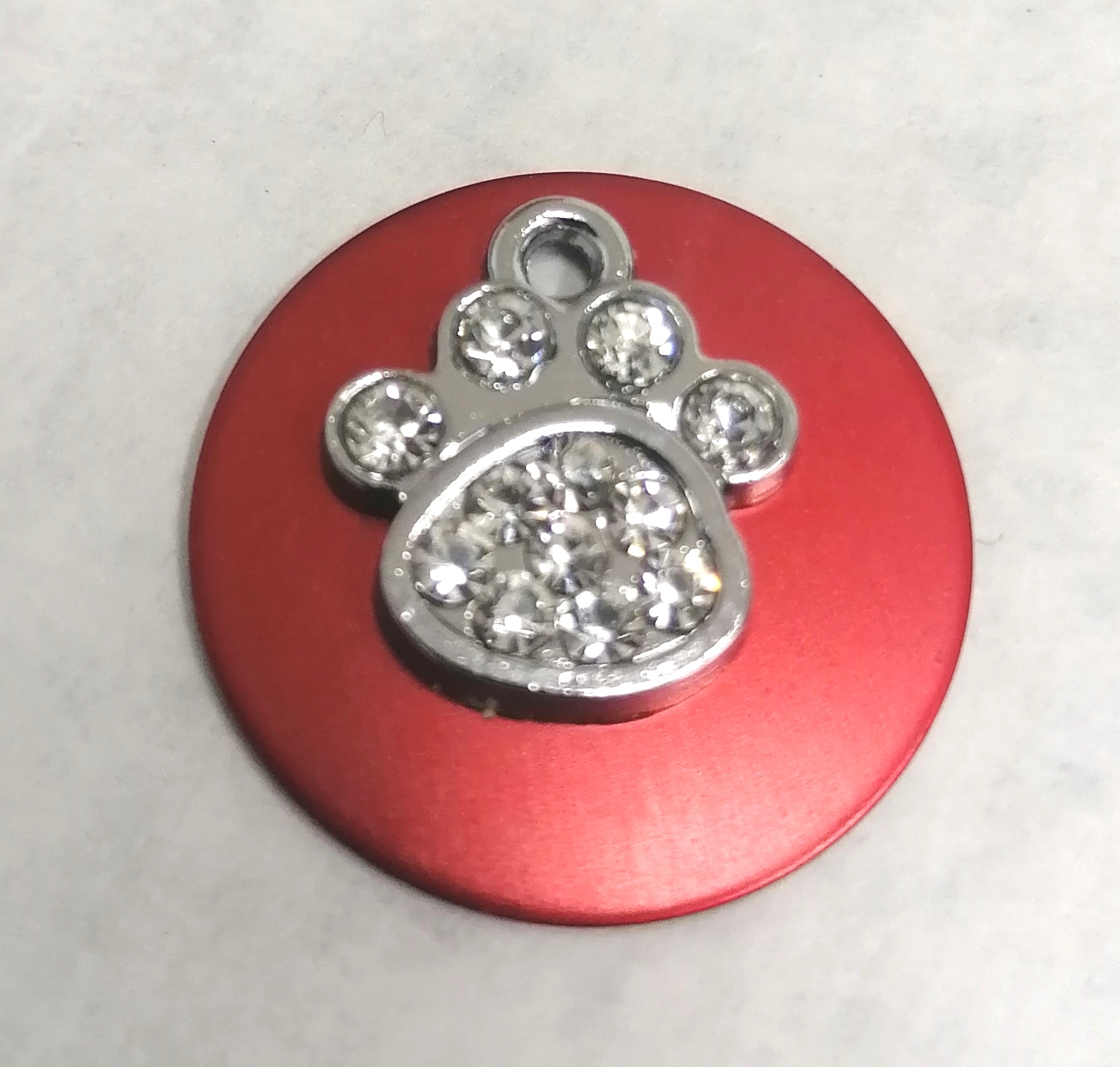 Disco vermelho com pendente em forma de pata com cristais