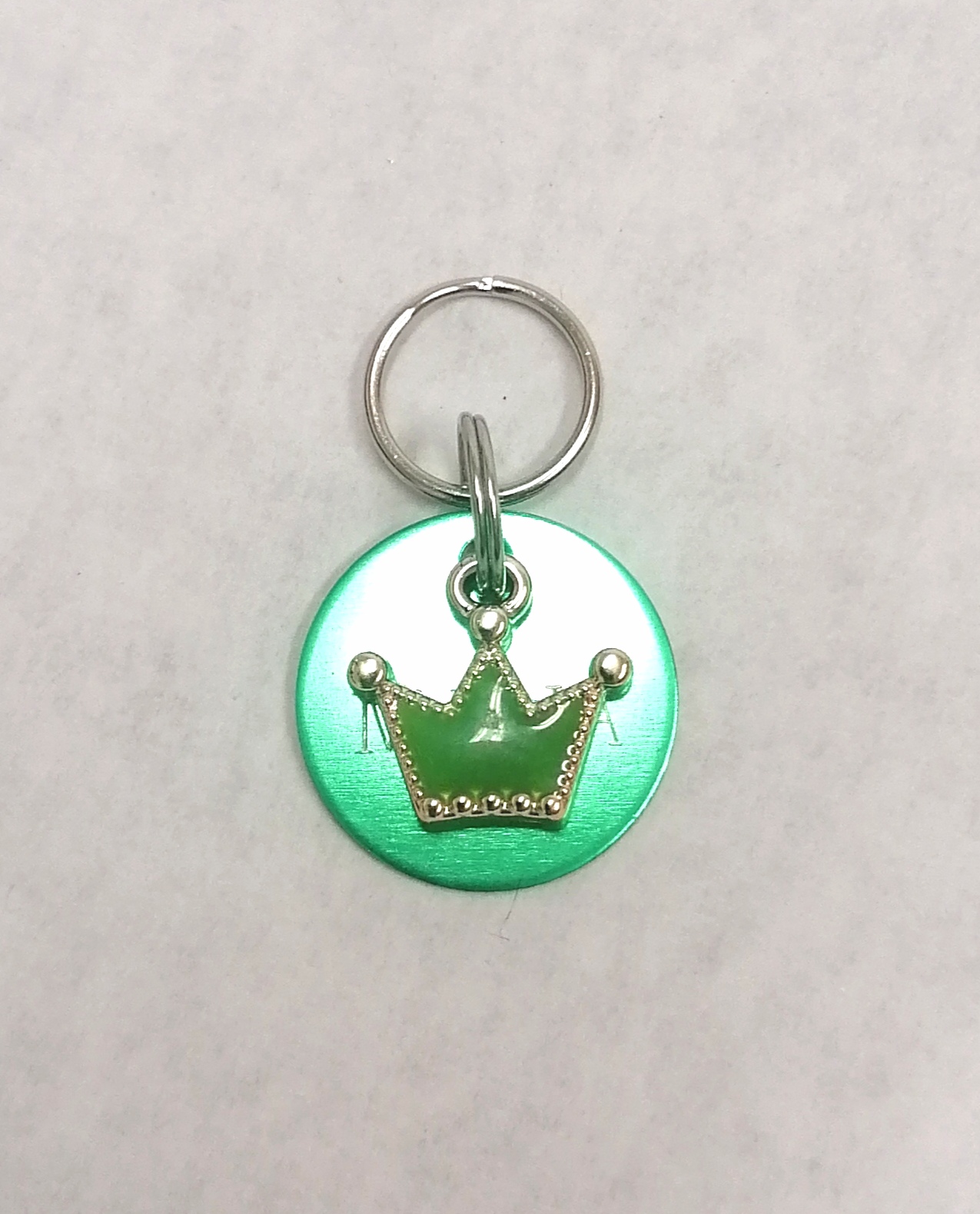 Chaveiro redondo verde com coroa dourada e anel metálico prateado