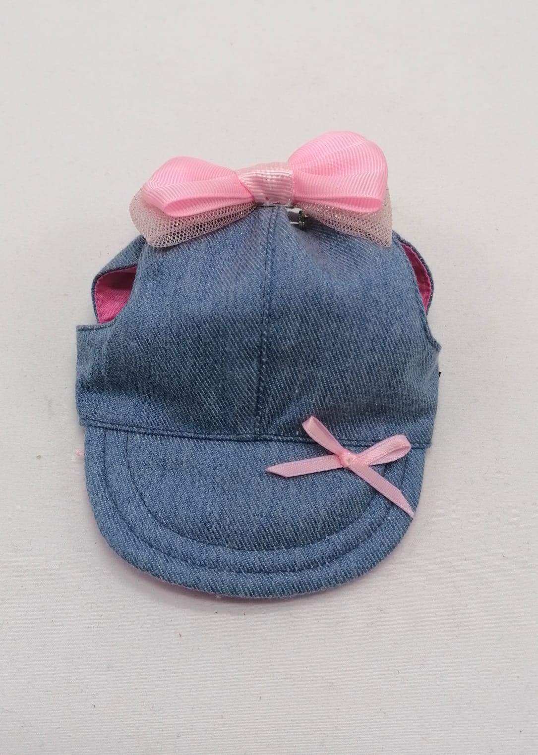 Boné de ganga azul com dois laços cor-de-rosa, um grande na parte superior e outro pequeno na pala