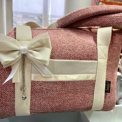 Bolsa cor de rosa com alças e laço branco decorativo numa superfície de vidro