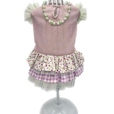 Vestido rosa de criança com saia floral e xadrez e colar de contas no manequim