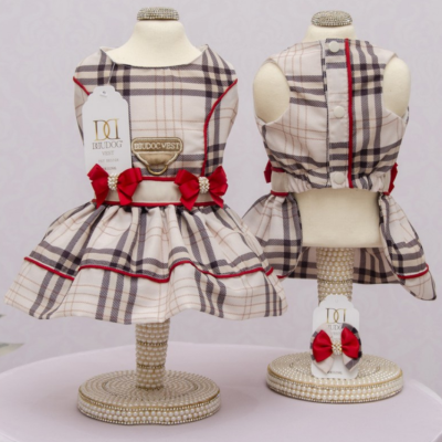 Vestido xadrez bege para cão com laços vermelhos em manequins decorativos.