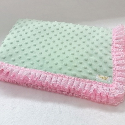 Manta verde clara texturizada com borda rosa rendada em fundo branco