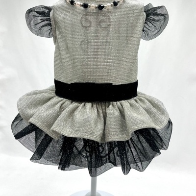 Vestido infantil branco com cintura preta e saia preta brilhante exibido num manequim branco