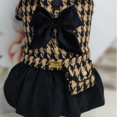 Vestido para cão pied-de-poule bege e preto com laço preto e saia preta num manequim decorado