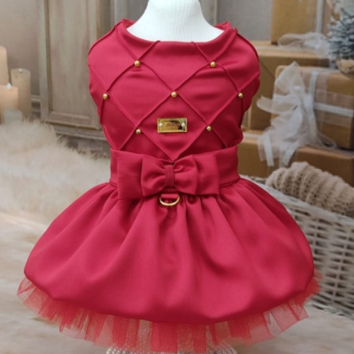 Vestido vermelho elegante com laço e detalhes dourados exposto num manequim