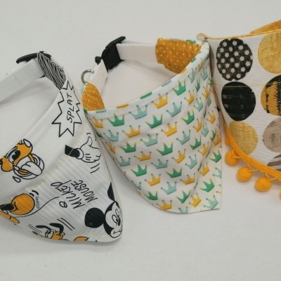 Três babetes triangulares coloridos com estampados e pompons