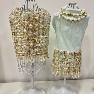 Dois manequins com roupas em tecido bouclé bege e verde claro com colar de contas