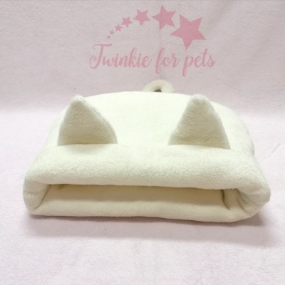 Cama felpuda branca para animais de estimação com orelhas, sobre tecido rosa e texto 'Twinkie for pets'.