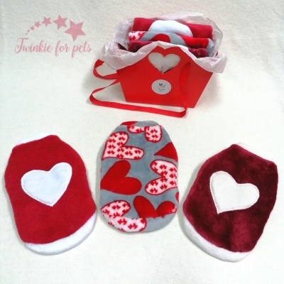 Roupinhas para pets com corações em vermelho, cinza e bordô junto a caixa vermelha com coração branco