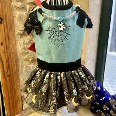 Vestido para cão verde água com detalhes pretos e padrão de personagens na saia.