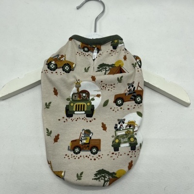 Roupa para cachorro bege com padrão de carros de safari e animais, pendurada em cabide branco