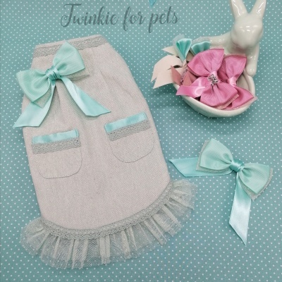 Roupinha para cão bege com laço azul-claro, dois laços decorativos e figura branca de coelho sobre fundo azul com bolinhas brancas