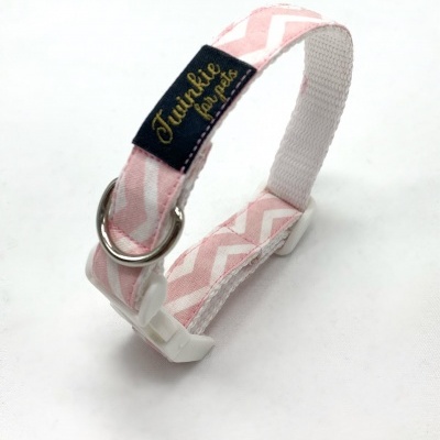 Coleira de cão rosa com padrão zig-zag e etiqueta preta com texto dourado