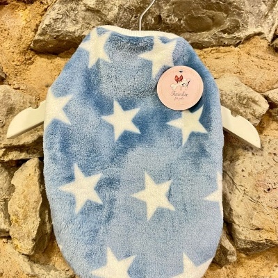 Roupa de cama para animal de estimação azul com estrelas brancas pendurada numa parede de pedra