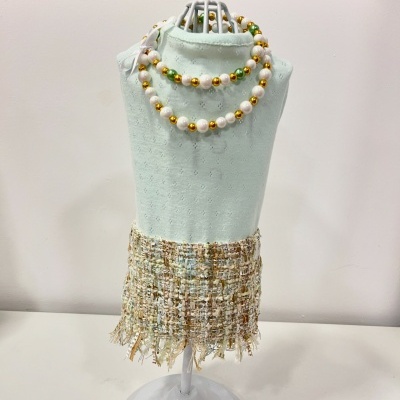 colar de contas peroladas e saia de tecido tweed em suporte verde claro