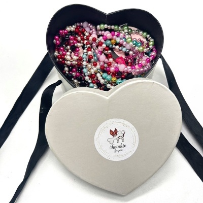 Caixa de coração branca com colares coloridos brilhantes dentro.