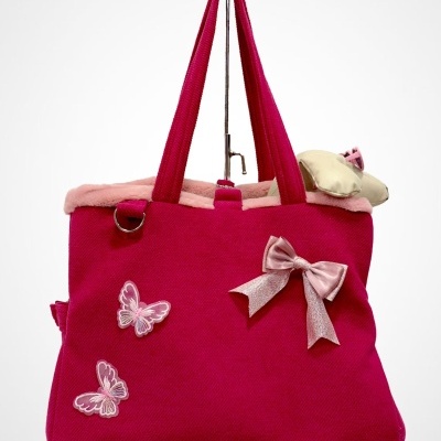 Mala cor-de-rosa com laço, borboletas bordadas e interior em pêlo rosa, pendurada em gancho