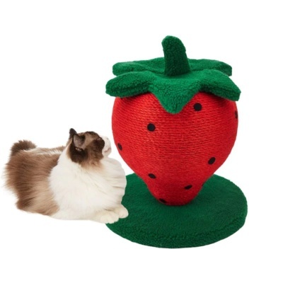 Arranhador para gatos em forma de morango vermelho com manchas pretas e folhas verdes ao lado de gato