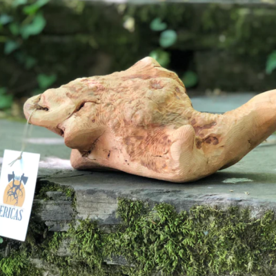 Escultura de madeira clara com etiqueta ERICAS sobre pedra musgosa