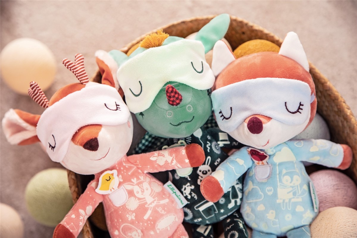 Três bonecos de pelúcia coloridos dentro de um cesto de tecido