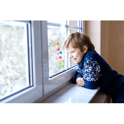 Menino com camisola azul a olhar pela janela adesivada