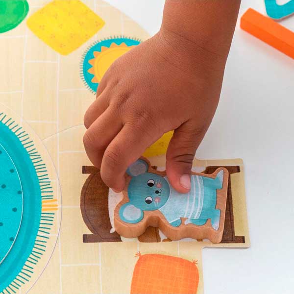 Peça de puzzle em madeira com rato azul sendo segurada por uma mão infantil