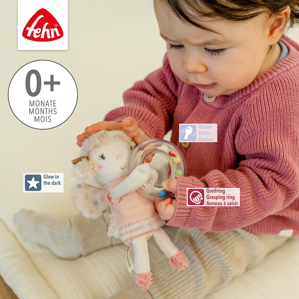 Bebé com casaco rosa segurando boneca de peluche branca com anel transparente e bolas coloridas