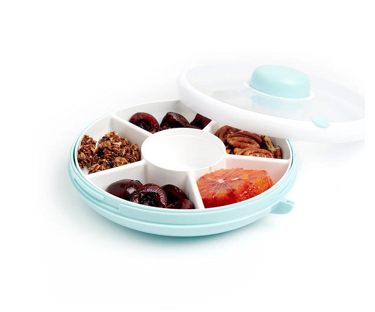 Tigela organizadora redonda com cinco compartimentos contendo alimentos variados e tampa transparente
