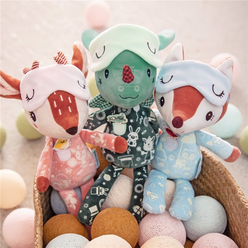 Três bonecos de tecido com pijamas e máscaras de dormir em cesta rodeada por bolas coloridas.