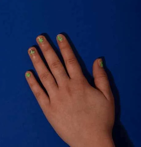 Mão com unhas pintadas de verde com desenhos