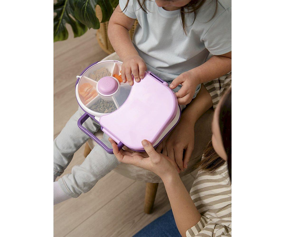 Porta-lanches rosa com compartimentos transparentes para snacks, manuseado por crianças.