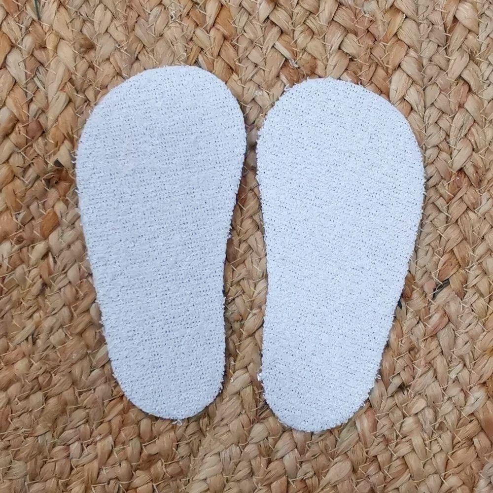 Palmilhas brancas sobre superfície têxtil bege entrelaçada