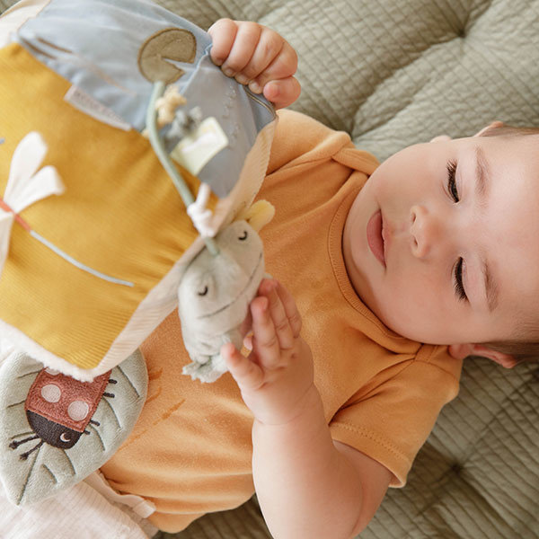 bebé deitado a brincar com brinquedo macio colorido