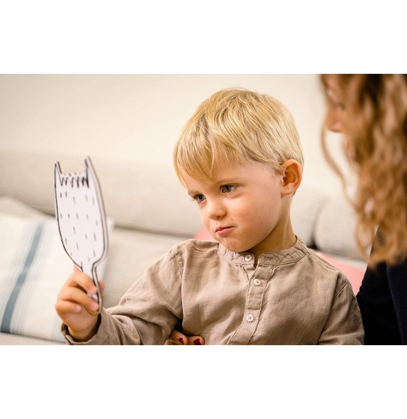Criança loira segura espelho branco formato gato sentado no sofá