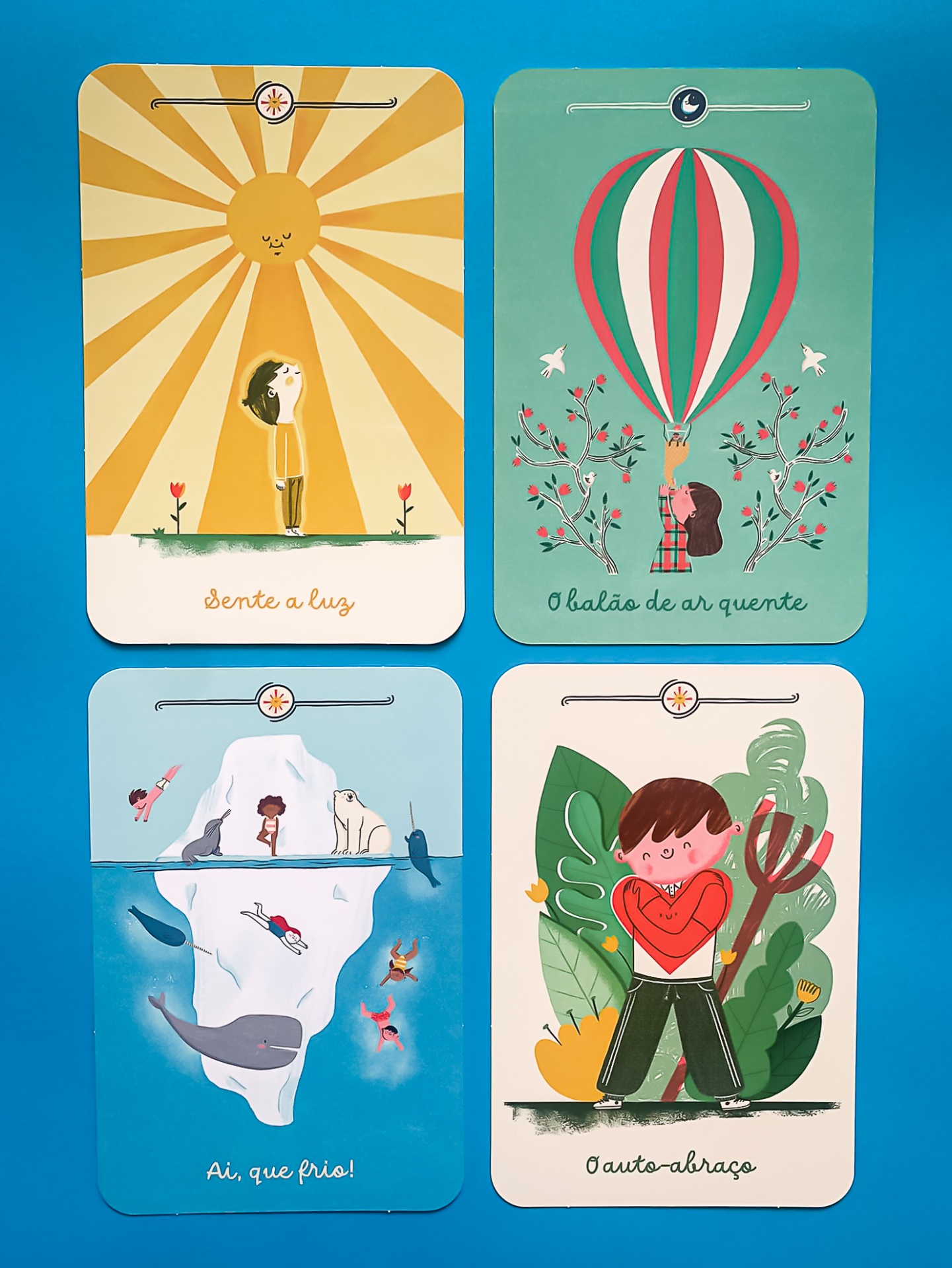 Quatro cartas ilustradas com desenhos infantis e textos em português relacionadas ao sol, balão, frio e abraço.