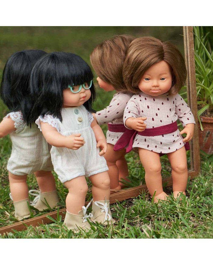 Duas bonecas com roupa branca e creme na relva ao lado de um espelho