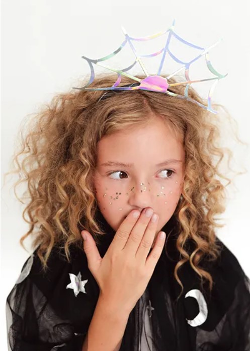 Criança com tiara de teia de aranha e capa preta com símbolos celestiais