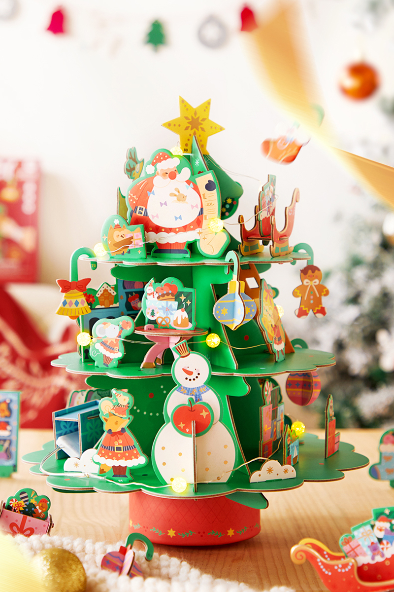 Árvore de Natal em papelão com figuras natalícias coloridas e luzes amarelas