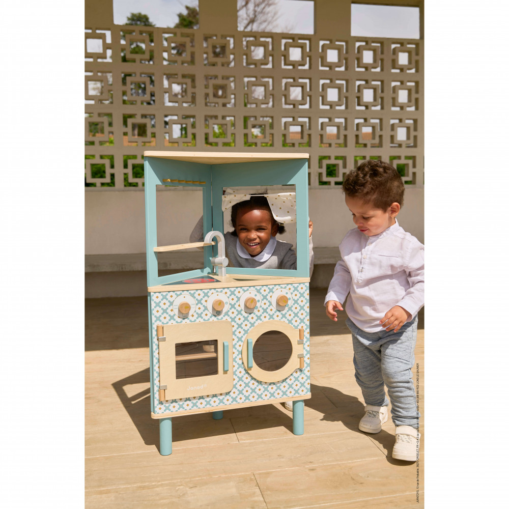 Brinquedo de cozinha em madeira azul e bege com duas crianças a brincar no exterior