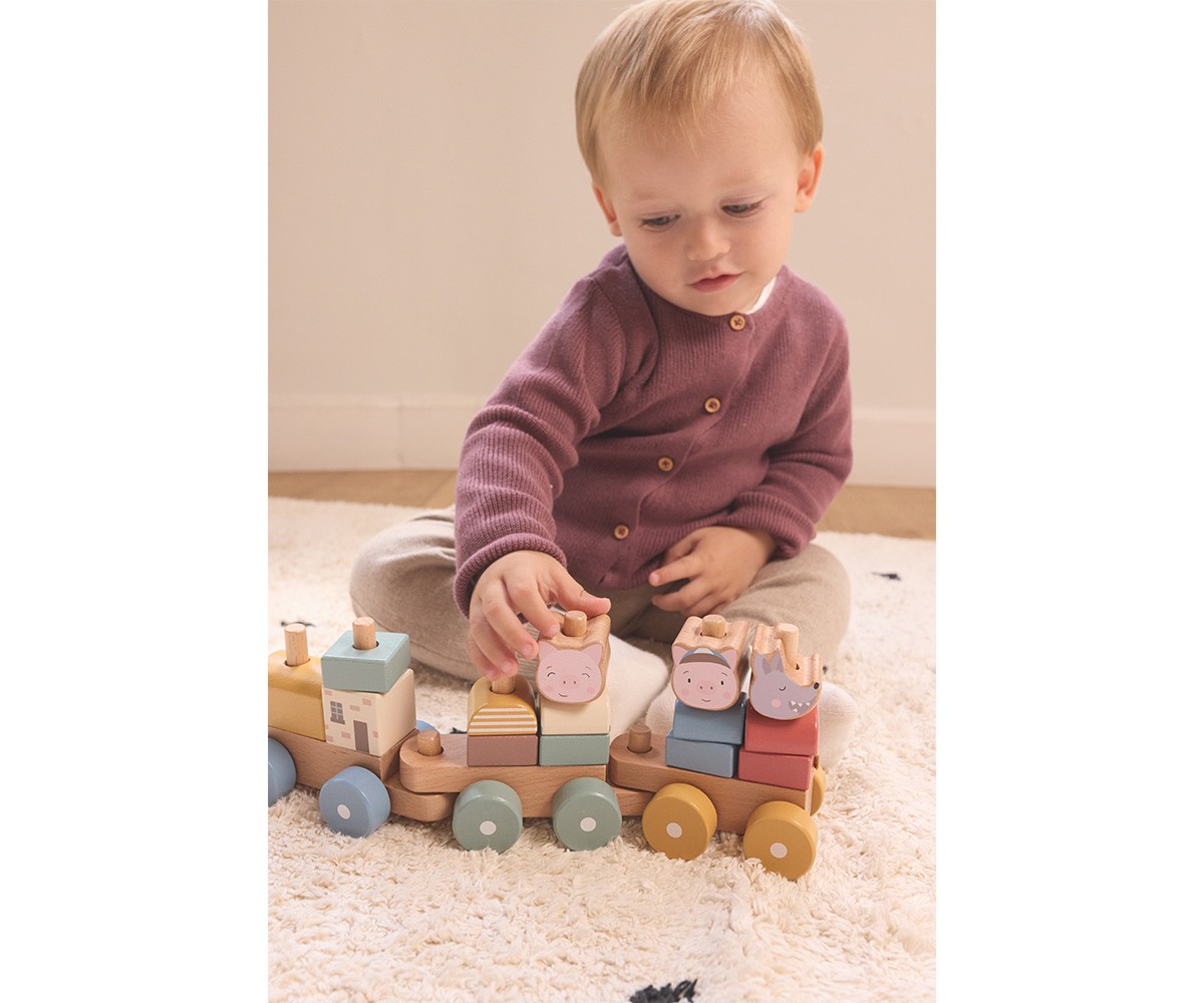 Criança a brincar com comboio de madeira colorido num tapete claro