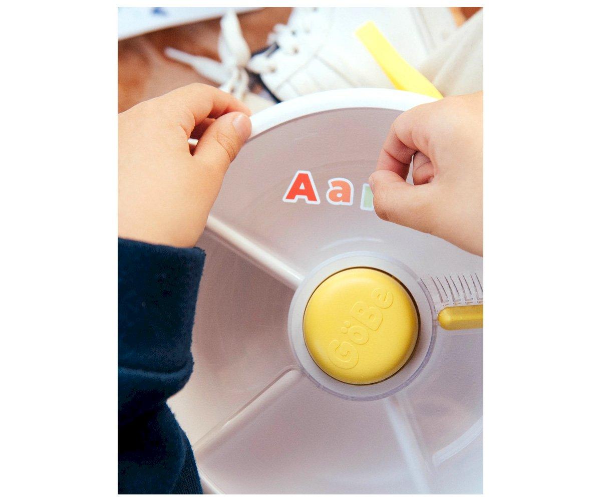 Brinquedo infantil giratório com botão amarelo e letras coloridas