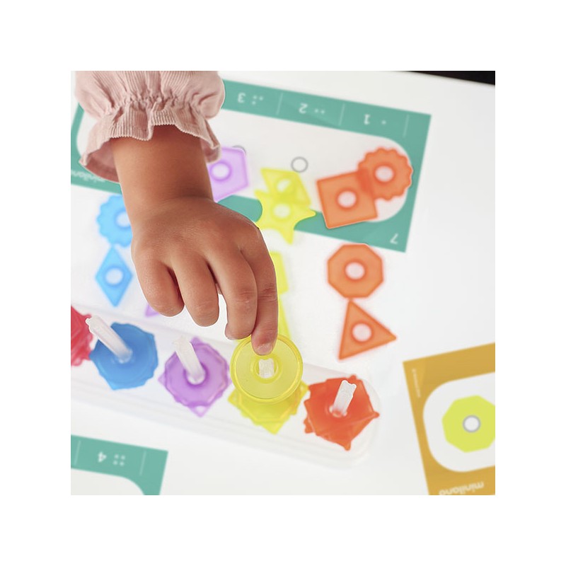 Peças coloridas de plástico em tabuleiro com mão de criança a segurar peça amarela