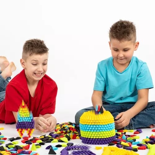 Crianças montando figuras coloridas com peças de construção plásticas no chão.