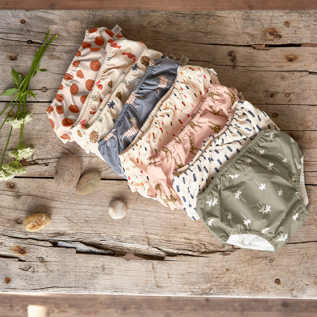 Conjunto colorido de capas para fraldas reutilizáveis com padrões variados sobre madeira rústica