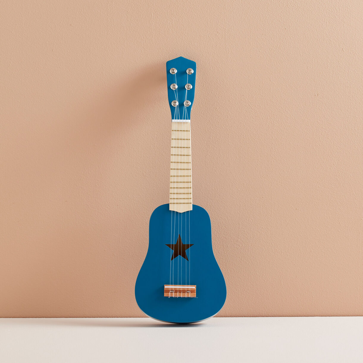 Ukulele azul com orifício em forma de estrela contra fundo bege