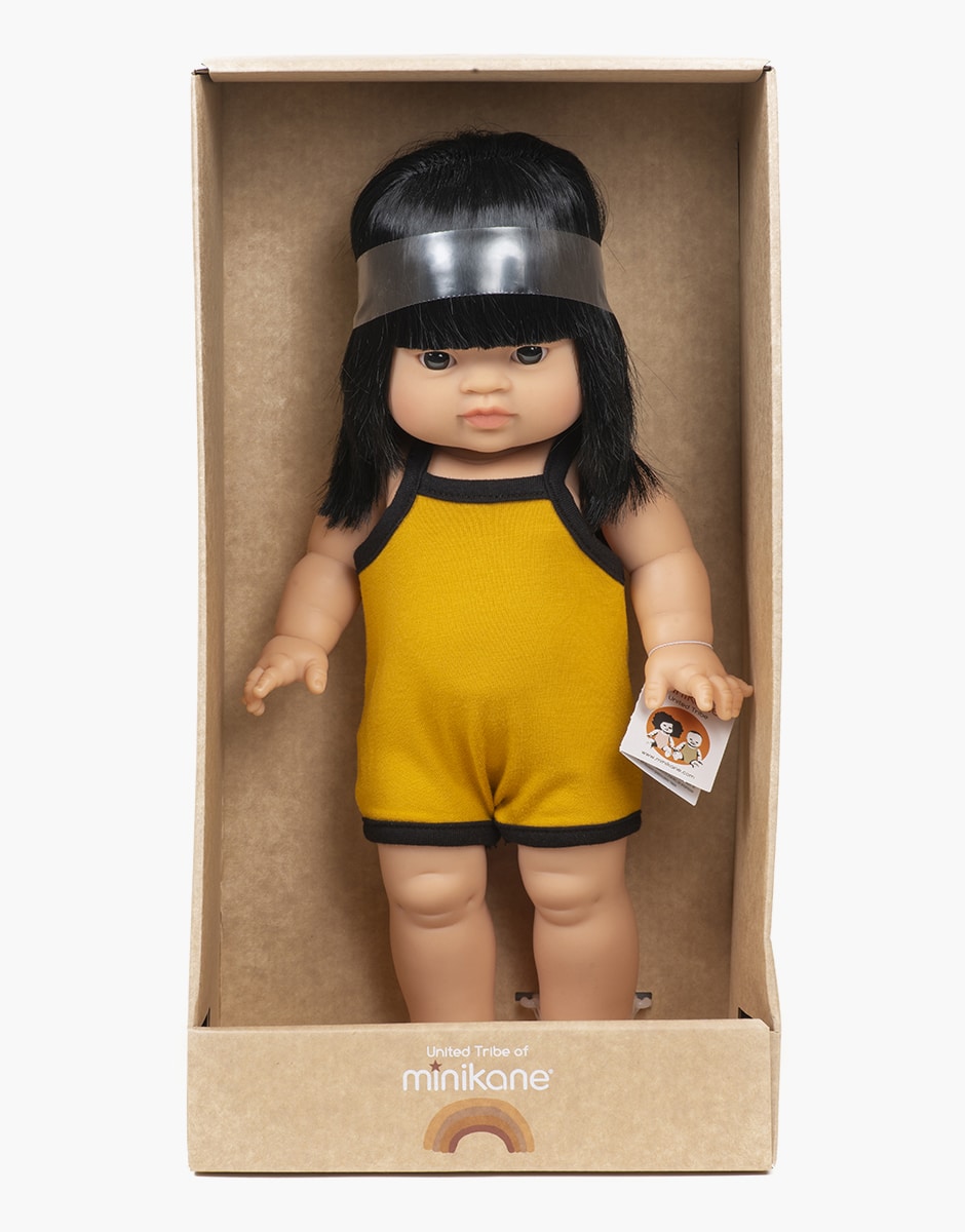 Boneca com macacão amarelo numa caixa de papelão